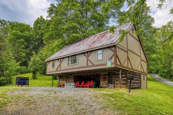 Un bâtiment de style rustique, rappelant une grange, avec un toit en pente, une véranda couverte et une allée gravillonnée.