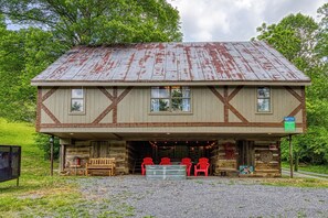 Une cabane rustique avec une façade en bois, une véranda avec des chaises rouges et une petite table.
