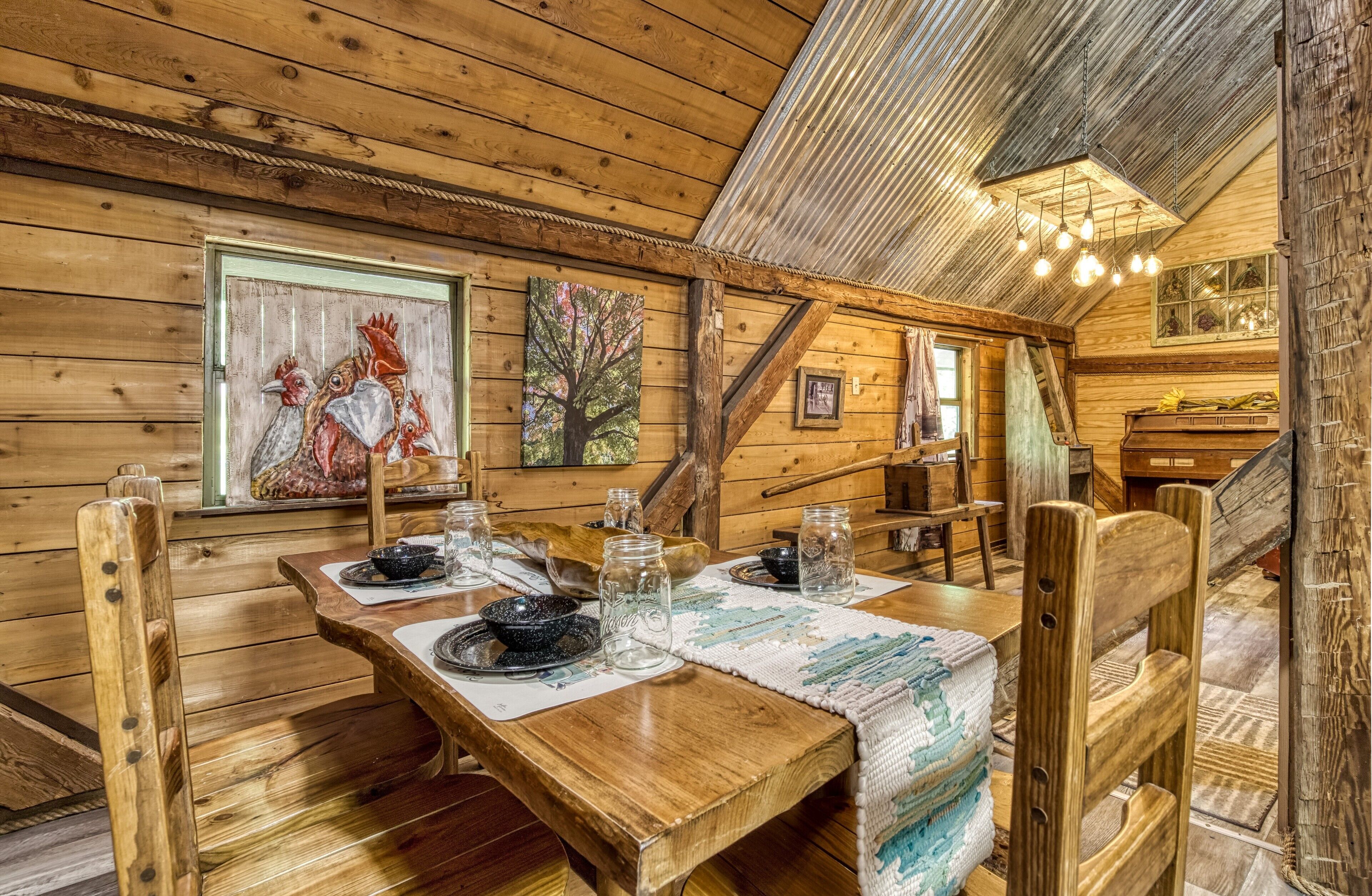 A rustic wooden dining area with a table set for two, wooden chairs, and a ceiling with exposed beams.