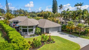 A residential property with a large house, a covered patio, and a well-maintained garden with various plants and trees. - Laule'a 'Ohana Hale - Luxurious 'Ohana home with A/C (Princeville)
