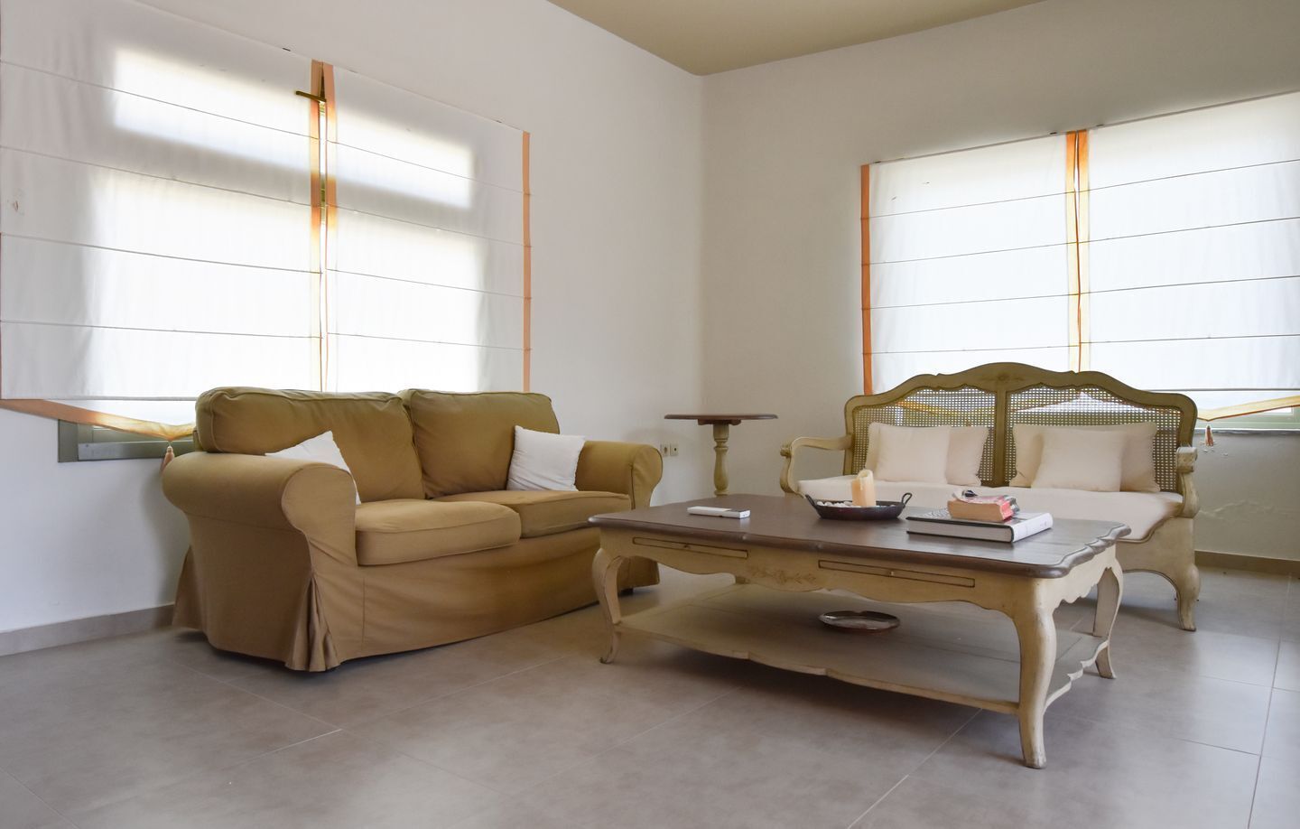 Un salon avec un canapé beige, une table basse en bois et un fauteuil de style vintage.