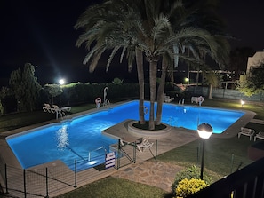 A rectangular swimming pool with a decorative edge, surrounded by a fence, palm trees, and outdoor seating. - Apartment 817 on the waterfront with a view of the sea (Marbella)