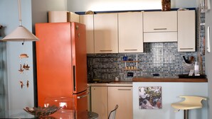 Eine Küche mit einem Glastisch, einem roten Kühlschrank und einer gefliesten Spritzschutzwand.