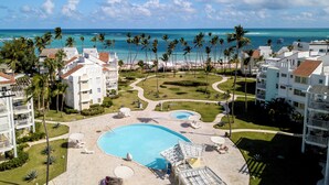 Un resort con una piscina grande, palmeras y vista al océano.