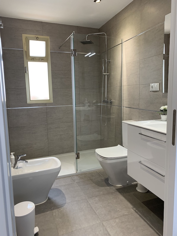 A modern bathroom with a glass-enclosed shower, a freestanding bathtub, and a toilet.