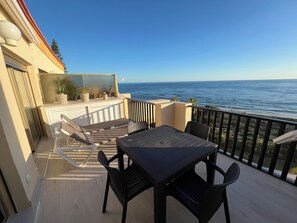 En balkon med bord og stole med udsigt over havet.