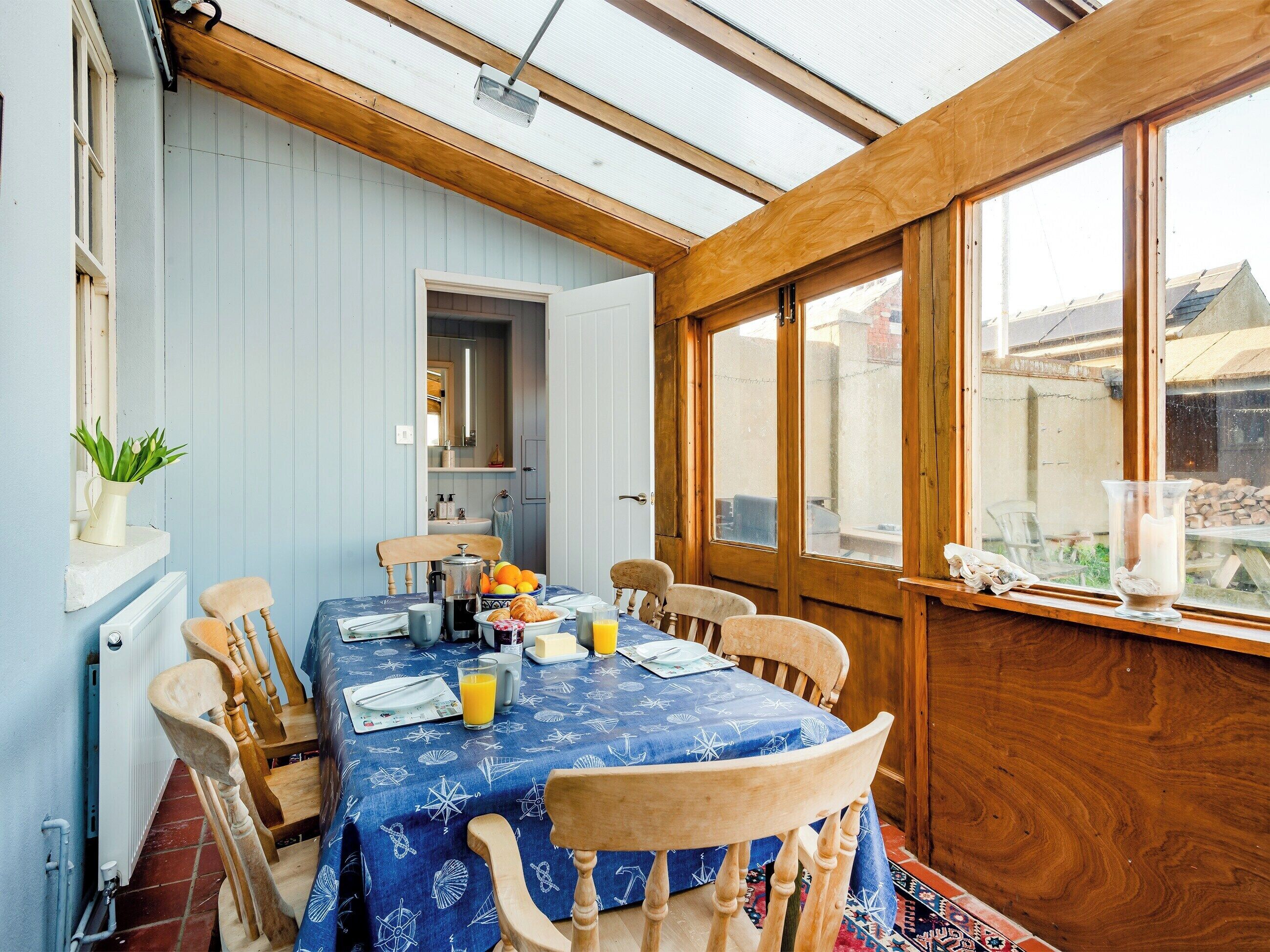 A dining area with a table set for breakfast, including a pitcher of juice, a plate of eggs, and a bowl of fruit.