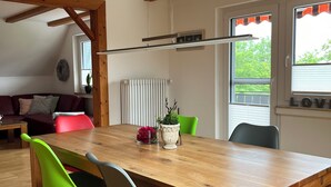 Et spiseområde med et træbord, fire stole, en potteplante og en radiator.