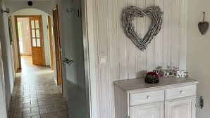 En gang med en hvid dør, en hjerteformet dekoration og et skab med skuffer.
