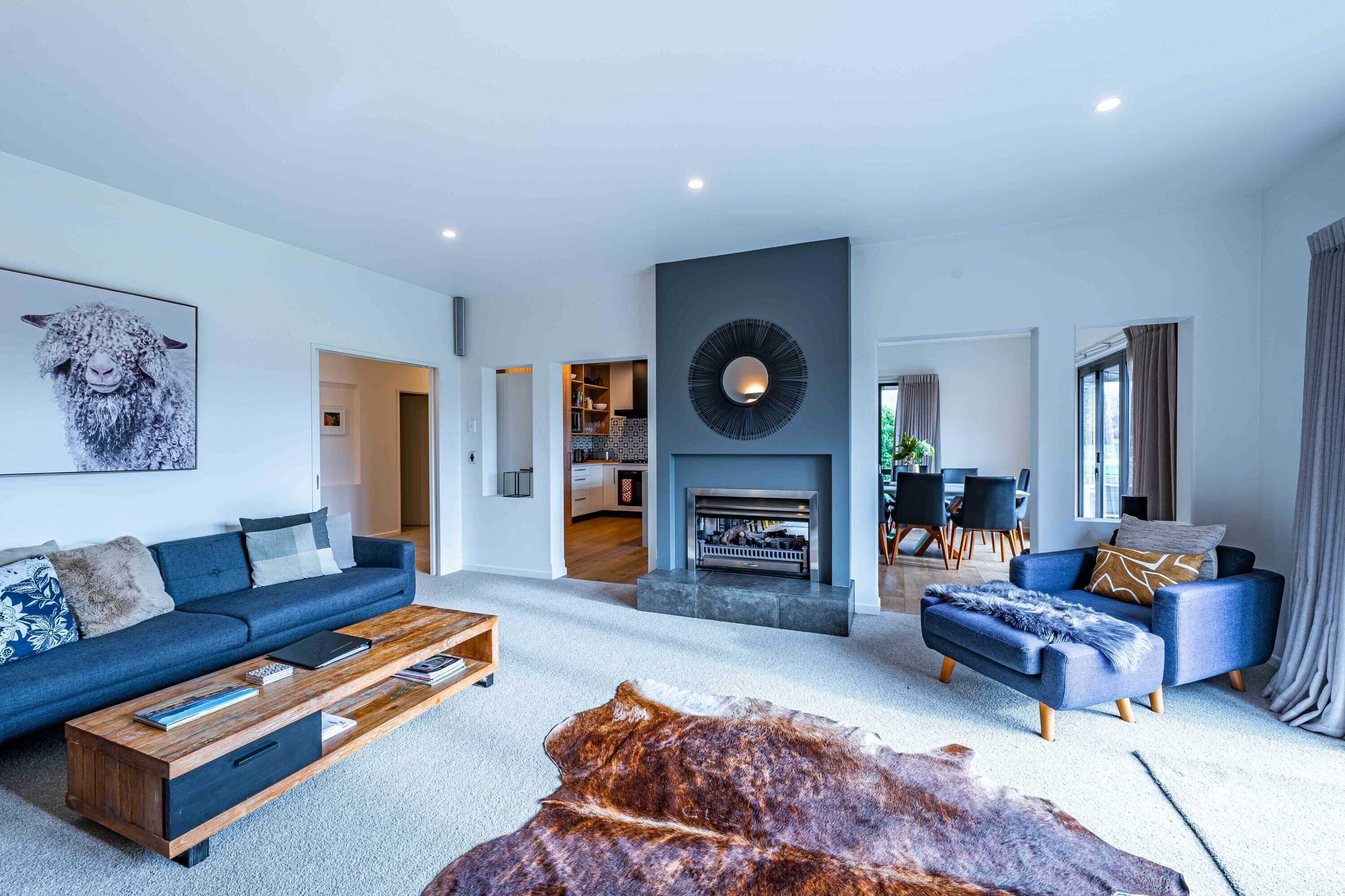 A modern living room with a sofa, ottoman, coffee table, and a fireplace.