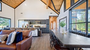 Una cocina amplia con electrodomésticos modernos, un comedor con una mesa larga y sillas, y una zona de estar acogedora con un sofá de cuero.