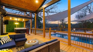 Un espacio al aire libre techado con piscina, terraza de madera y asientos.