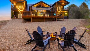Una cabaña de madera con terraza, mobiliario exterior y un brasero.