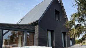 Una casa moderna con jacuzzi, ventanas amplias y terraza de madera.