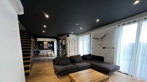 Una sala de estar moderna con una mesa de centro de madera, un sofá modular y una escalera que sube a un nivel superior.