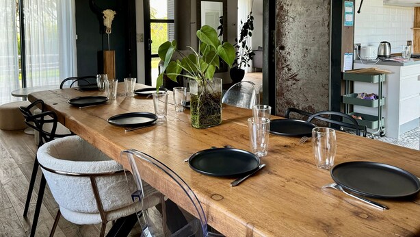 Una mesa de comedor dispuesta con platos, vasos y una planta en maceta.