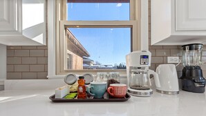 Een keuken met een koffiezetapparaat, blender en diverse keukenbenodigdheden op een dienblad.