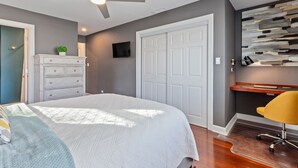 Een slaapkamer met een bed, een dressoir en een bureau met stoel.