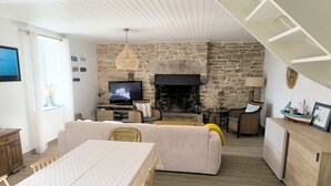 A modern living room with a stone wall, a fireplace, and a television. - Ploemeur 56, Kerroch 150m from the sandy beach (Ploemeur)
