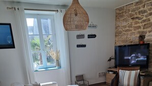 A living room with a sofa, a coffee table, a television, and a stone wall. - Ploemeur 56, Kerroch 150m from the sandy beach (Ploemeur)