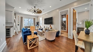 A spacious living room with a blue sofa, wooden coffee table, and a ceiling fan. - Upscale Destin Escape Pool Golf Cart Beach Access (Miramar Beach)