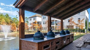 A covered outdoor area with a wooden deck, a water fountain, and barbecue grills. - Upscale Destin Escape Pool Golf Cart Beach Access (Miramar Beach)