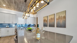 A modern kitchen with white cabinets, a large island, and a hanging light fixture. - Upscale Destin Escape Pool Golf Cart Beach Access (Miramar Beach)