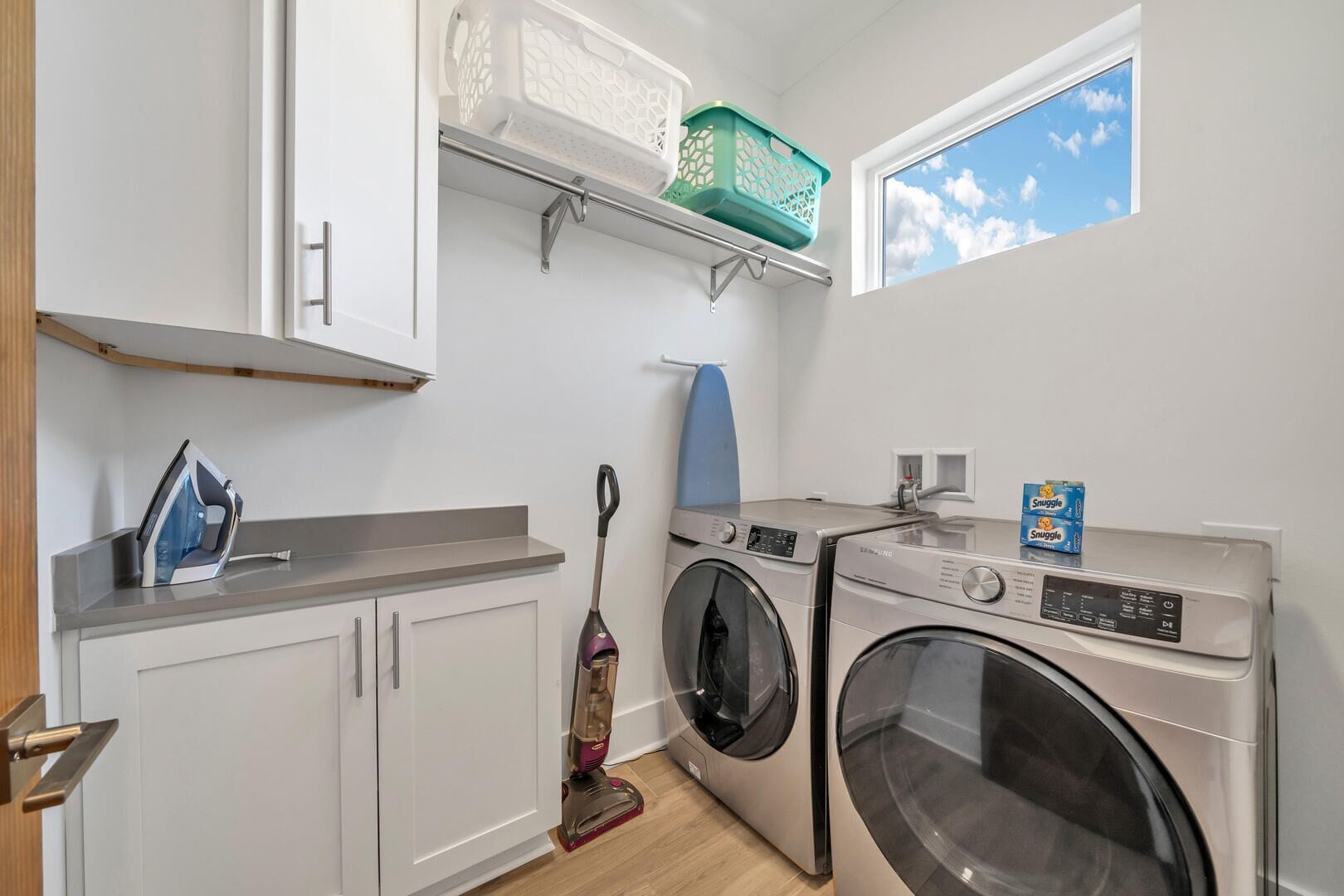 Une buanderie équipée d’un lave-linge, d’un sèche-linge, d’un fer à repasser et d’un aspirateur.