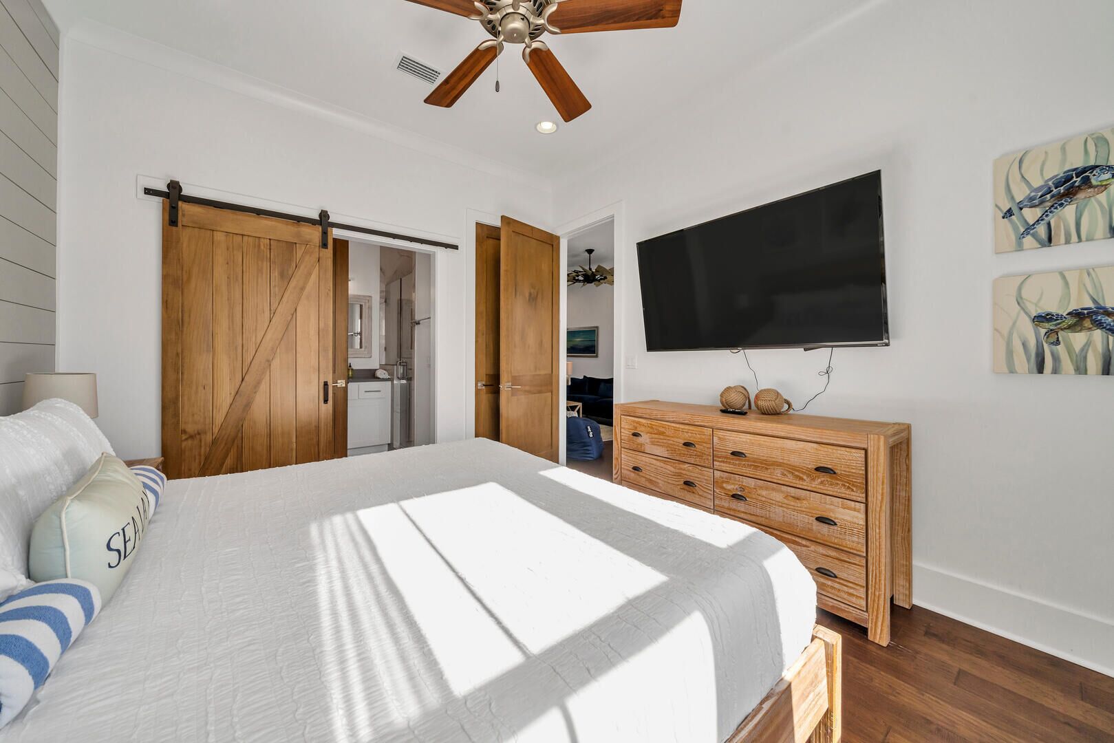 A bedroom with a large bed, wooden wardrobe, a TV, and artwork on the wall.