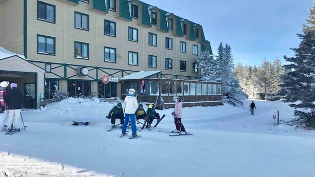 Un hotel de varios pisos con una pista de esquí frente a él.
