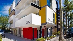 Kerrostalo, jossa on parvekkeita, punainen sisäänkäynti ja kyltti, jossa lukee ”Villa Luccheese”.