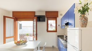 Cocina compacta con comedor, refrigerador y ventana con vista a un balcón.