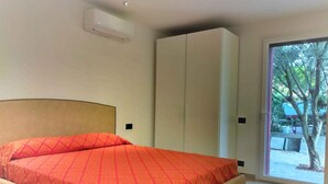 A bedroom with a bed, a wardrobe, and a sliding glass door leading to an outdoor area.