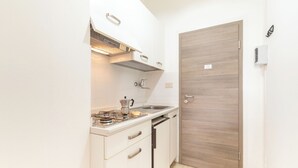 Een kleine keuken met witte kastjes, een kookplaat en een spoelbak.