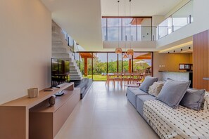 Sala de estar moderna com sofá, televisão e espaço de jantar.