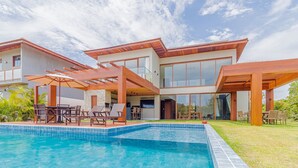A modern house with a swimming pool, outdoor seating, and large windows. - PF47 High Standard House 5 Suites - Praia do Forte (Mata de São João)