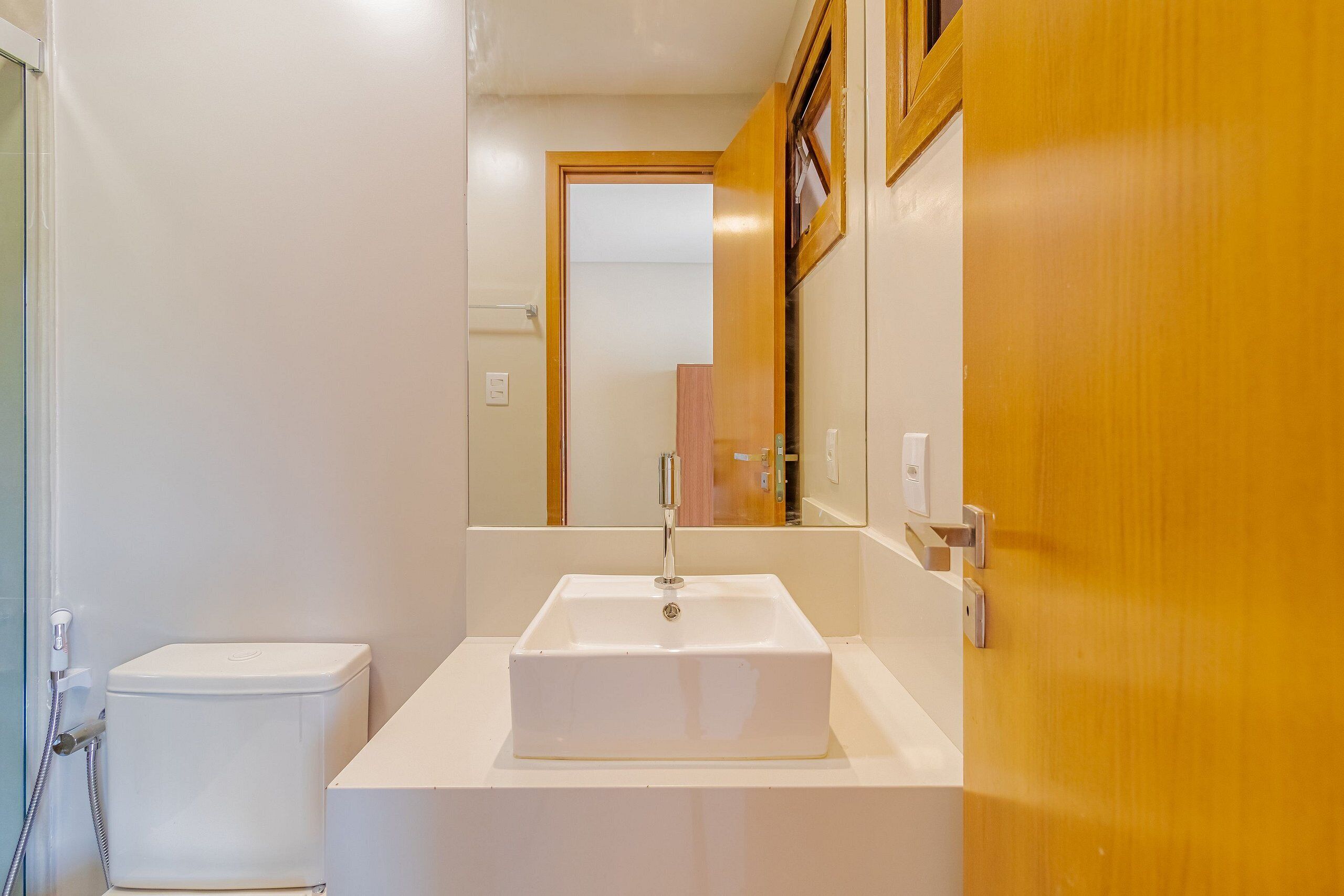 A bathroom with a white sink, a toilet, and a mirror.