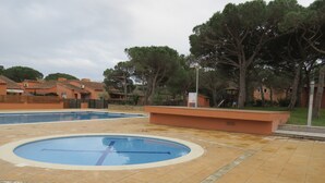 A swimming pool area with a tiled deck, a small pool, and a play structure.