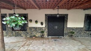 Zona exterior àmplia amb sòl de pedra, sostre de fusta i una porta negra.