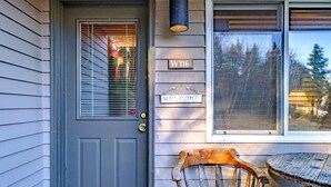 A gray door with a window, a wooden chair, a small round table, and a welcome sign with a house number. - Maybe the best location on the mountain! Pool, hot tub, sleeps 6! (Newry)