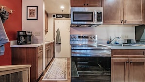 A compact kitchen with wooden cabinets, a stainless steel microwave, an oven, and a coffee maker. - Maybe the best location on the mountain! Pool, hot tub, sleeps 6! (Newry)