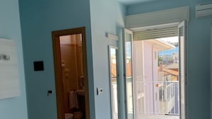 A spacious room with a ceiling fan, a large window, and a view of a balcony. - Hotel Mirabella (Cattolica)
