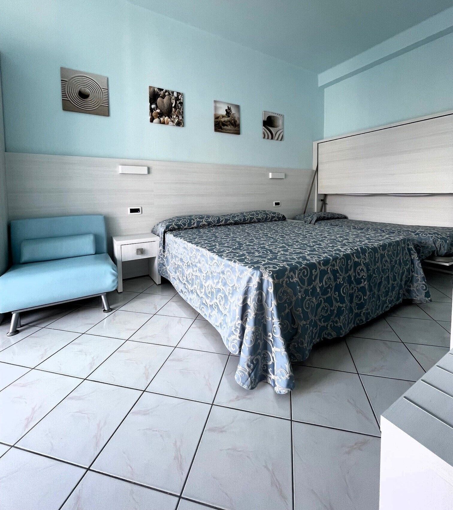 A bedroom with a bed, a sofa, and a nightstand.