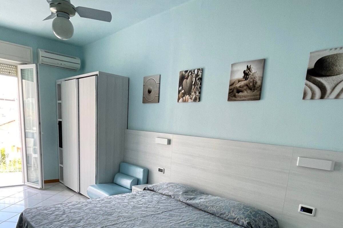 A bedroom with a bed, a nightstand, a wardrobe, and a ceiling fan.