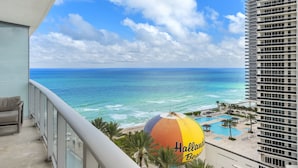 Vista da praia a partir de uma varanda com vista para uma área de piscina e um guarda-sol com a inscrição 'Halls Beach'.