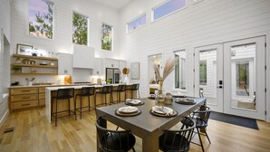 Una cocina amplia con una isla central, suelo de madera y armarios blancos.
