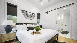 Un dormitorio con cama, mesita de noche, lámpara y ventana con vistas.