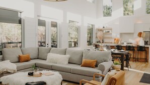 Una sala de estar moderna con un sofá gris, un suave plaid blanco y sillas de madera.