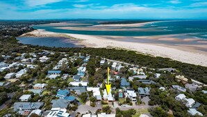 An aerial view of a coastal residential area with houses, a beach, and a large body of water.