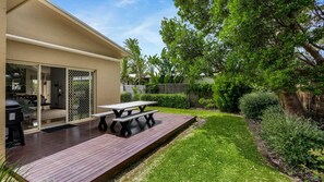 Enjoy an outdoor space with a deck and picnic table amidst lush landscaping.